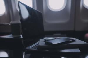 attraktiv asiatisch weiblich Passagier von Flugzeug Sitzung im komfortabel Sitz Hören Musik- im Kopfhörer während Arbeiten beim modern Laptop Computer mit spotten oben Bereich mit kabellos Verbindung auf Tafel. foto