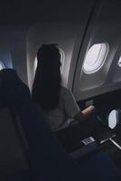 Silhouette von Frau sieht aus aus das Fenster von ein fliegend Flugzeug. Passagier auf das Flugzeug ruhen neben das Fenster. foto