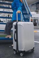 jung asiatisch Frau im International Flughafen, mit Handy, Mobiltelefon Smartphone und Überprüfung Flug beim das Flug Information Tafel foto