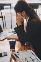 asiatische frauen sind gestresst, während sie am laptop arbeiten, müde asiatische geschäftsfrau mit kopfschmerzen im büro, sich bei der arbeit krank fühlen, kopierraum foto