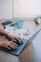 Porträt einer asiatischen jungen Frau, die im Büro am Laptop arbeitet foto