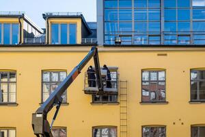 zwei Mechaniker Mann auf hydraulisch Kran mit reparieren Fenster foto