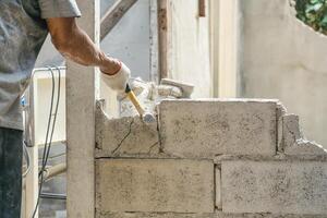 Hand von Arbeiter mit Hammer zerschlagen und zerstören auf Backstein Mauer beim Konstruktion Seite? ˅ foto