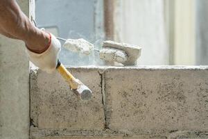 Hand von Arbeiter mit Hammer zerschlagen und zerstören auf Backstein Mauer beim Konstruktion Seite? ˅ foto