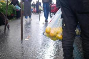 Person mit Plastik Tasche voll von Zitronen Gehen auf Straße Oberfläche foto