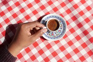 oben Aussicht von halten ein ein Tasse von Türkisch Kaffee auf Tabelle foto