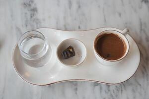 ein Tasse von Türkisch Kaffee, Freude und Glas von Wasser auf Fliesen Hintergrund foto