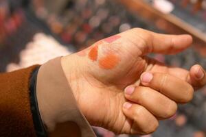 ein Geste von bewirbt sich karminrot Lippenstift zu das Fleisch von Ein weiterer Personen Hand foto