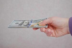 weiblich Hände halten Dollar Banknoten auf ein grau Hintergrund. foto