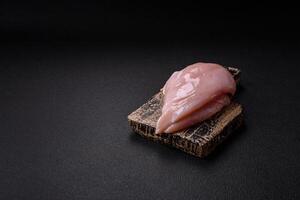 frisches Hühnerfilet auf dunklem Betontisch mit Gewürzen und Kräutern foto