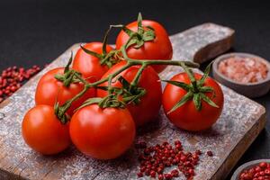 frisch rot Kirsche Tomaten auf ein Ast auf ein dunkel Beton Hintergrund foto