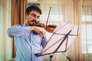 Mann spielen Violine beim heim. er ist Reinigung seine Instrument. foto