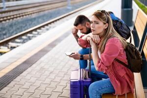 Ängstlich und müde Paar Sitzung beim Eisenbahn Bahnhof und warten zum Ankunft von ihr Zug. foto