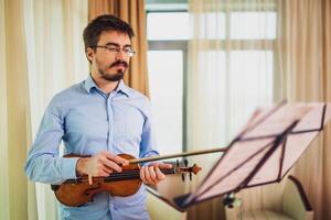 Mann spielen Violine beim heim. er ist Reinigung seine Instrument. foto