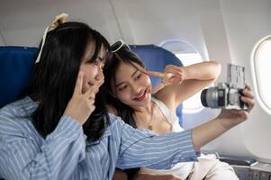 zwei glücklich asiatisch weiblich Passagiere sind nehmen ein Selfie zusammen während das Flug. foto