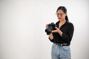ein zuversichtlich, erfahren asiatisch weiblich Fotograf ist einstellen ihr dslr Kamera, vorbereiten Fotoshooting Ausrüstung, und Arbeiten im das Studio. foto
