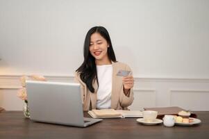 ein attraktiv asiatisch Geschäftsfrau ist Registrieren ihr Anerkennung Karte auf das Webseite foto