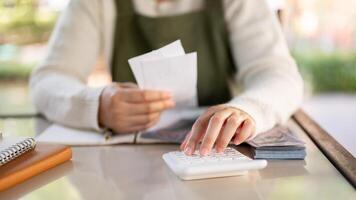 ein weiblich klein Geschäft Inhaber mit ein Taschenrechner, rechnen Rechnungen, Planung ihr Geschäft Kosten. foto