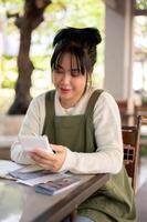 ein positiv asiatisch weiblich klein Geschäft Inhaber mit ein Taschenrechner, rechnen ihr Geschäft Einnahmen. foto