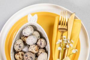 schließen oben Ostern Tabelle Rahmen im Weiß Gelb Farben. Geschirr, natürlich Wachtel Eier, golden Besteck. foto