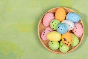 Farbe dekorativ Ostern Eier auf hölzern Teller auf Grün Gelb Hintergrund. oben Sicht. Kopieren Raum. foto