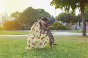 Frau umarmen ihr Haustier im ein Öffentlichkeit Garten beim Sonnenuntergang. Hund Liebhaber. foto