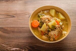 Hähnchen Suppe mit Gemüse im ein tief Schüssel auf ein hölzern Tisch. foto