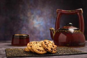 Vanille Schokolade Chip Kekse mit Tee einstellen im das Hintergrund auf hölzern Tisch. foto