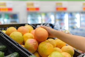 Hand halten ein Grapefruit im ein Supermarkt. foto