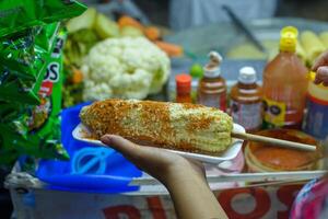 Mexikaner Frau vorbereiten ein gekocht Mais, typisch Mexikaner Straße Lebensmittel. Essen Stall. Elote. foto