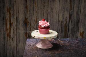 Cupcake auf klein Keramik Teller mit hölzern Unterseite mit Kopieren Raum. Produkt Foto. foto