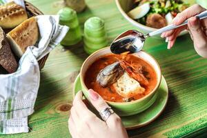 Person Essen ein Schüssel von Suppe mit ein Löffel foto