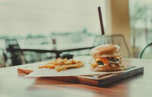 traditionell Hamburger mit Fritten serviert auf ein Restaurant Tisch. appetitlich Burger mit Fritten serviert auf ein hölzern Tabelle foto