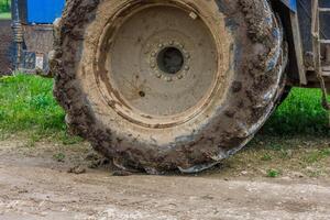 schmutzig doppelt Rad von ein groß Landwirtschaft Traktor auf Schmutz Straße beim Sommer- Tag foto