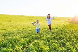 heiter und glücklich Kinder abspielen im das Feld und vorstellen sich zu Sein Piloten auf ein sonnig Sommer- Tag. Kinder Träume von fliegend und Luftfahrt. foto