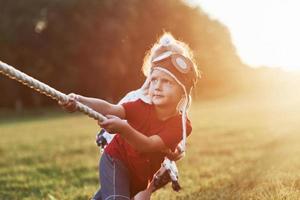 Es sieht einfach aus, aber vertrau mir, du musst es versuchen und du wirst deine Meinung ändern. das ist Tauziehen mit Papa auf schönem Gras eines sonnigen warmen Tages foto