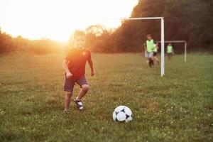 Ich kann den Torhüter von hier aus sehen, der Junge spielt an einem sonnigen warmen Tag Fußball und wird ein Tor schießen foto