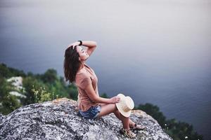 frische Luft. attraktives touristisches Mädchen posiert am Rande des Berges mit klarem Wassersee im Hintergrund foto