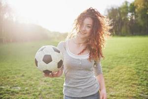 junges rothaariges sexy Mädchen im Gelegenheitsspieler im Fußballstadion bei Sonnenuntergang foto