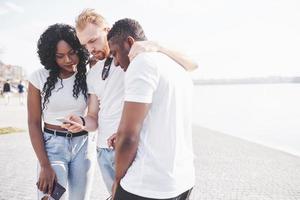 Gruppe von gemischtrassigen glücklichen Freunden, die im Freien Gadget verwenden. Konzept des Glücks und der multiethnischen Freundschaft zusammen gegen Rassismus foto