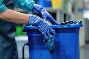 schließen oben von weiblich Reiniger im Handschuhe werfen Müll von Müll können in Plastik Eimer während foto