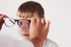 Spaß haben. Arzt gibt dem Kind eine neue schwarze Brille für seine Vision