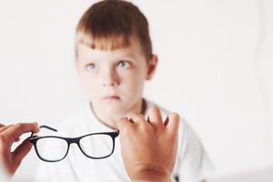 Aufmerksamkeit auf die Brille. Arzt gibt dem Kind eine neue schwarze Brille für seine Vision