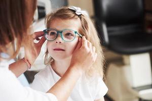 sitzt gut bei dir. Arzt gibt dem Kind eine neue Brille für seine Sehkraft
