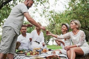 fröhliche Gesichter. Eine Gruppe erwachsener Freunde ruht sich zum Abendessen im Hinterhof des Restaurants aus und unterhält sich foto