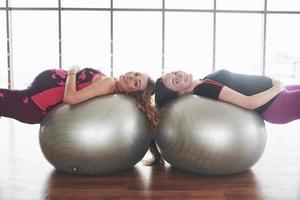 Mädchen im Fitnessstudio, die während der Schwangerschaft auf zwei Gymnastikbällen legen und lächeln foto