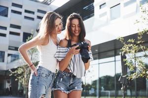 zwei hübsche hübsche Freundinnen des Mädchens mit der Kamera machen zusammen Fotos und gehen in der Stadt spazieren