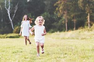 Mama und kleines Mädchen sind draußen auf dem Feld und im Wald im Hintergrund spazieren gegangen