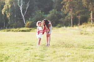 Kind, das mit einer Mutter im Freien über das Flugzeugspielzeug in ihren Händen spricht foto