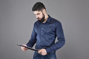 konzentrierter junger attraktiver Geschäftsmann in blauem Hemd, der in der Zwischenablage plant und schreibt